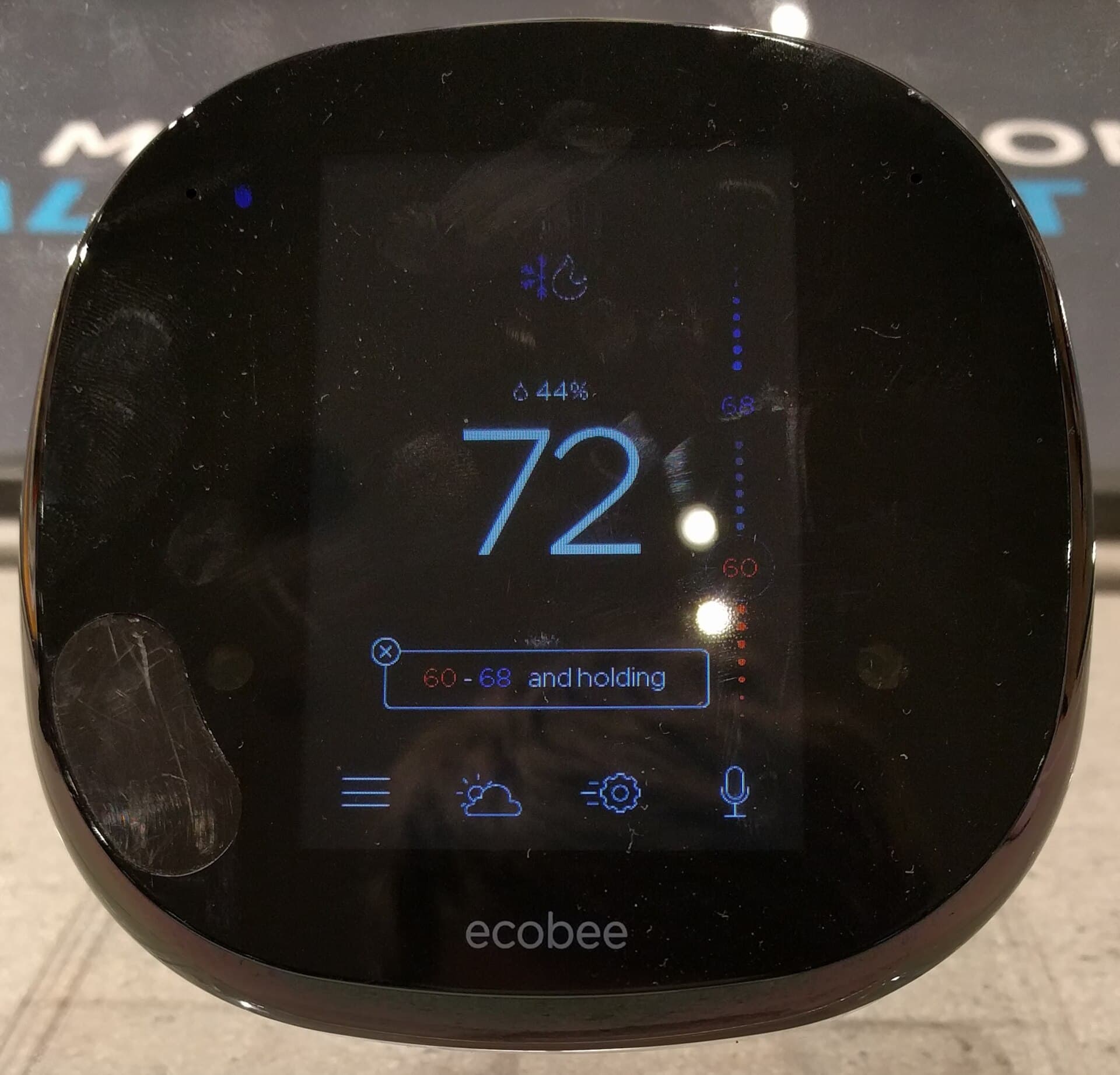 Smart thermostat mounted on a wall showing a temperature and efficiency readout