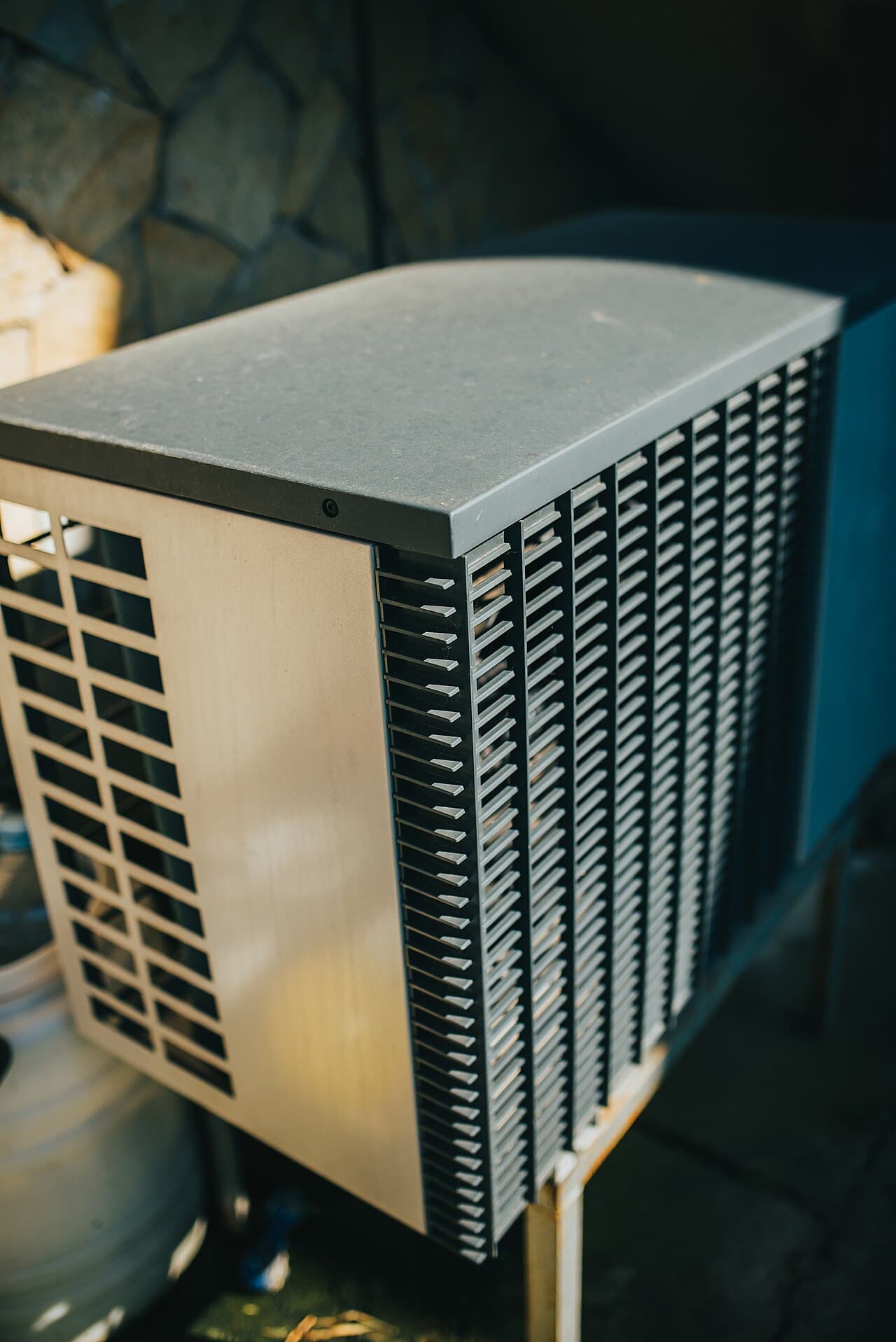 Outdoor condensing unit installed in a residential garden beside a house